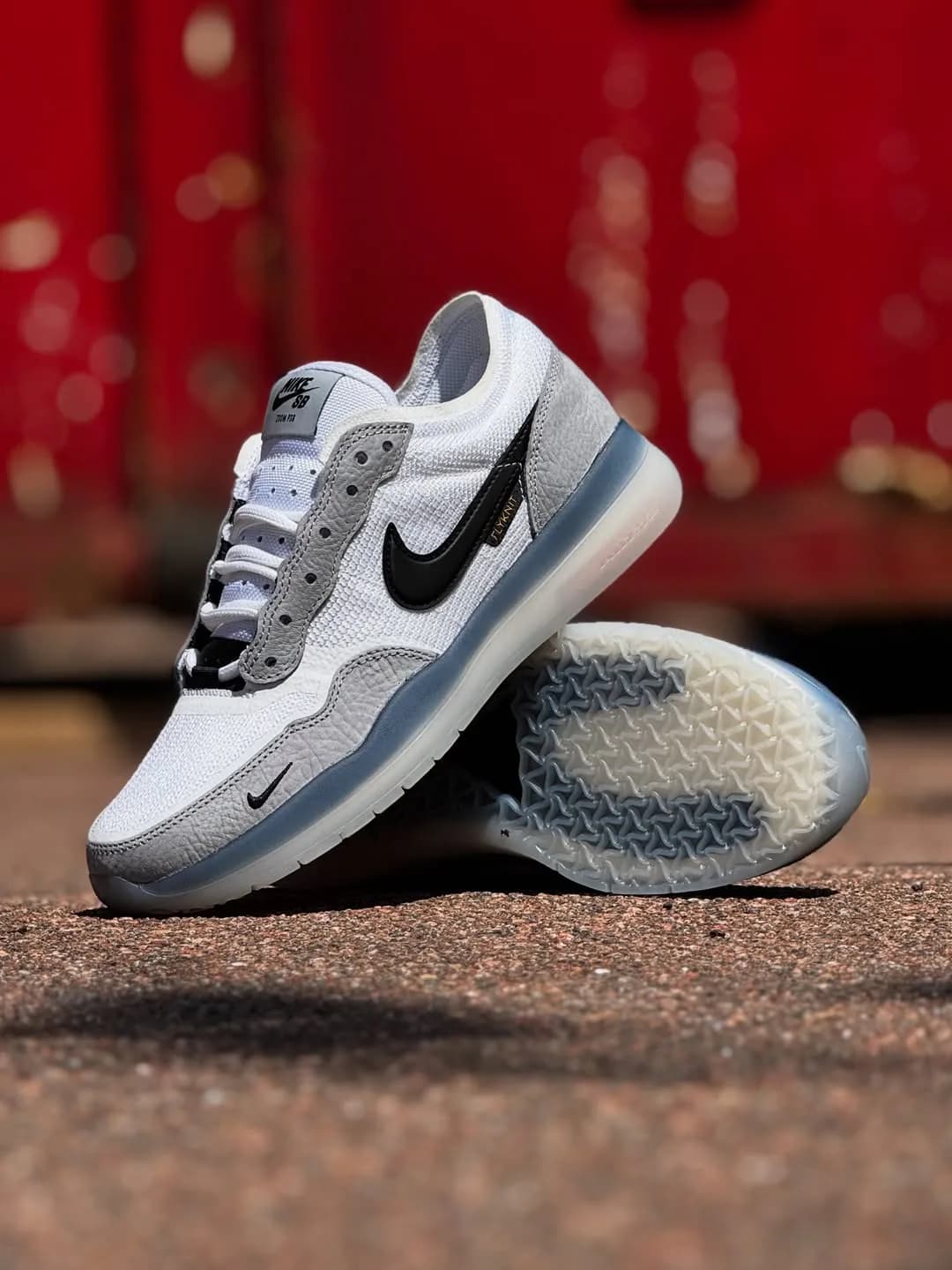 White and gray Nike SB Flyknit sneakers with black Swooshes and translucent soles