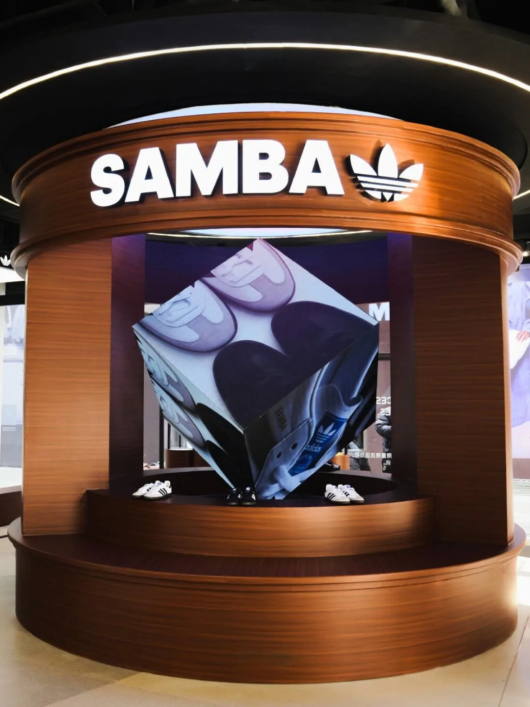 Circular wood Samba display with a rotating cube covered in sneaker images