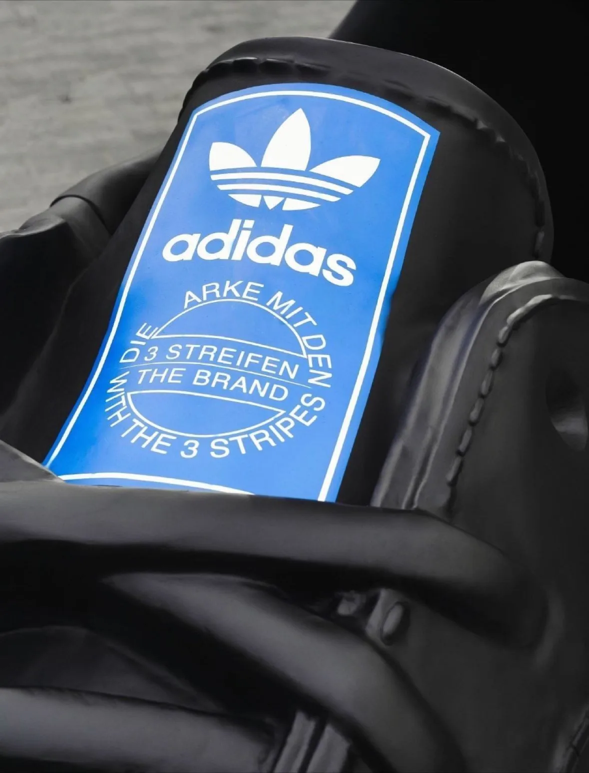 Blue Adidas Trefoil label on an oversized black Samba tongue installation