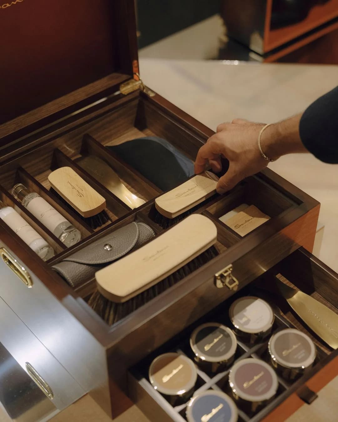 Santoni leather-care brushes and creams arranged inside a wooden case