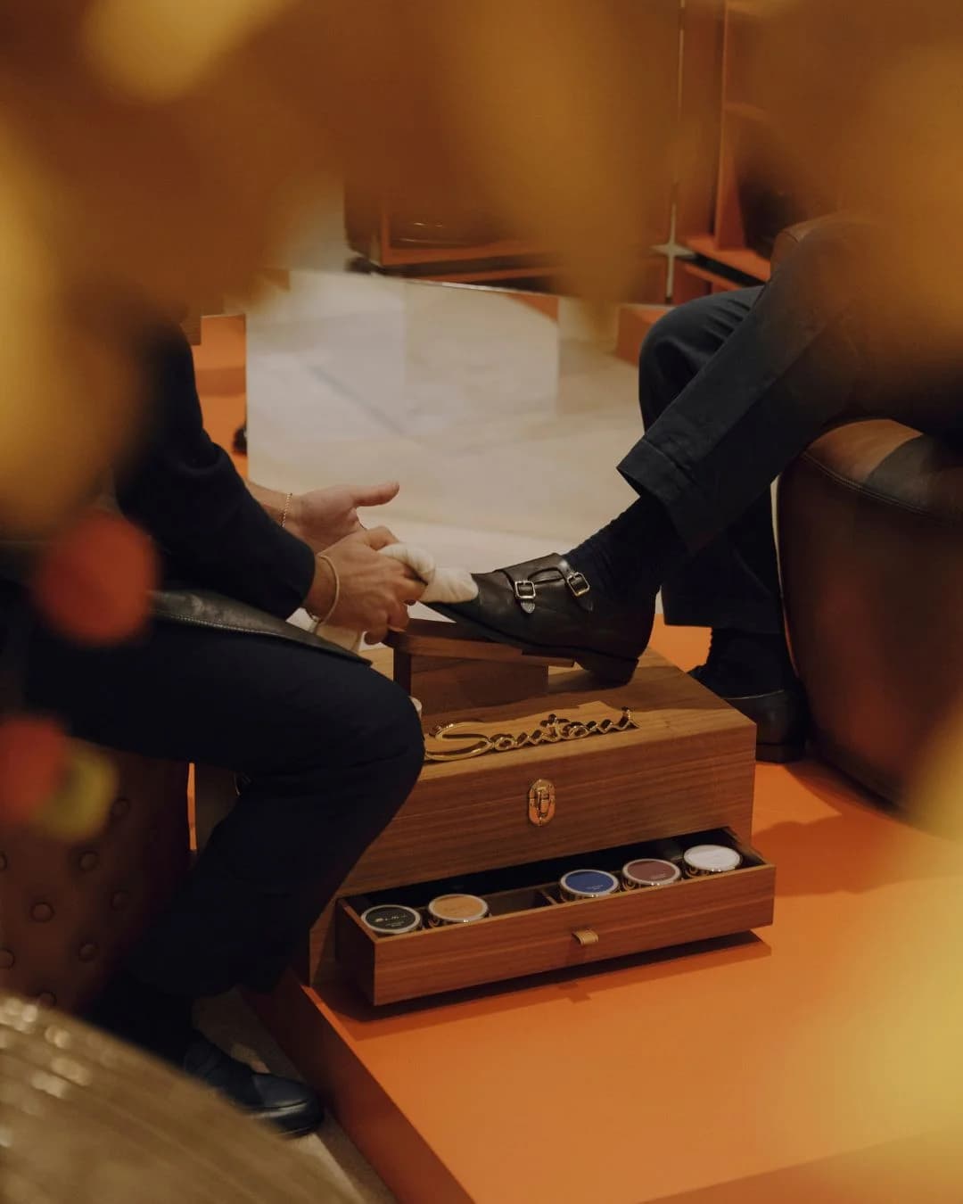 Santoni shoeshine service polishing a black double-monk shoe