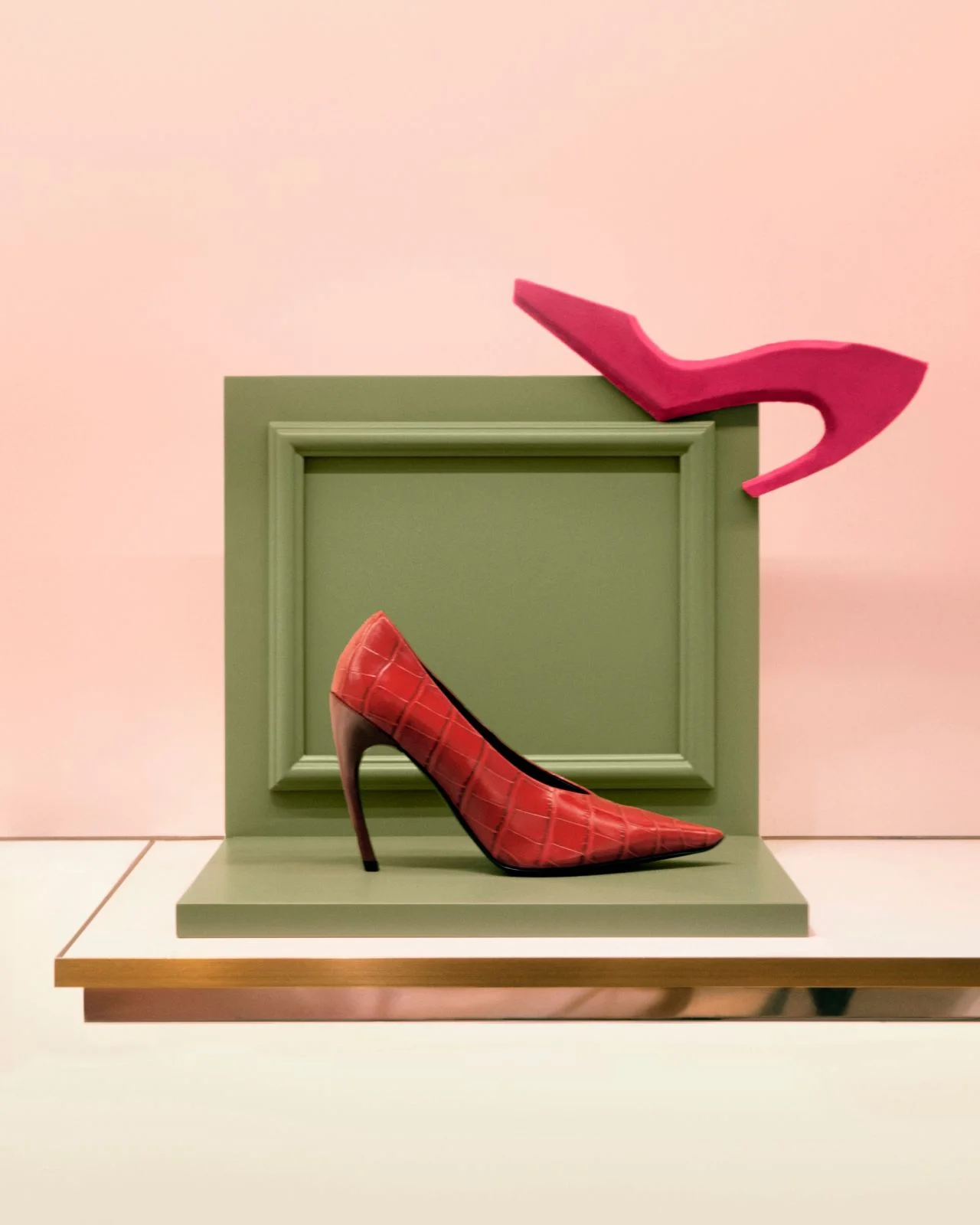 Red Roger Vivier Choc heel pump displayed against green and pink sculptural set