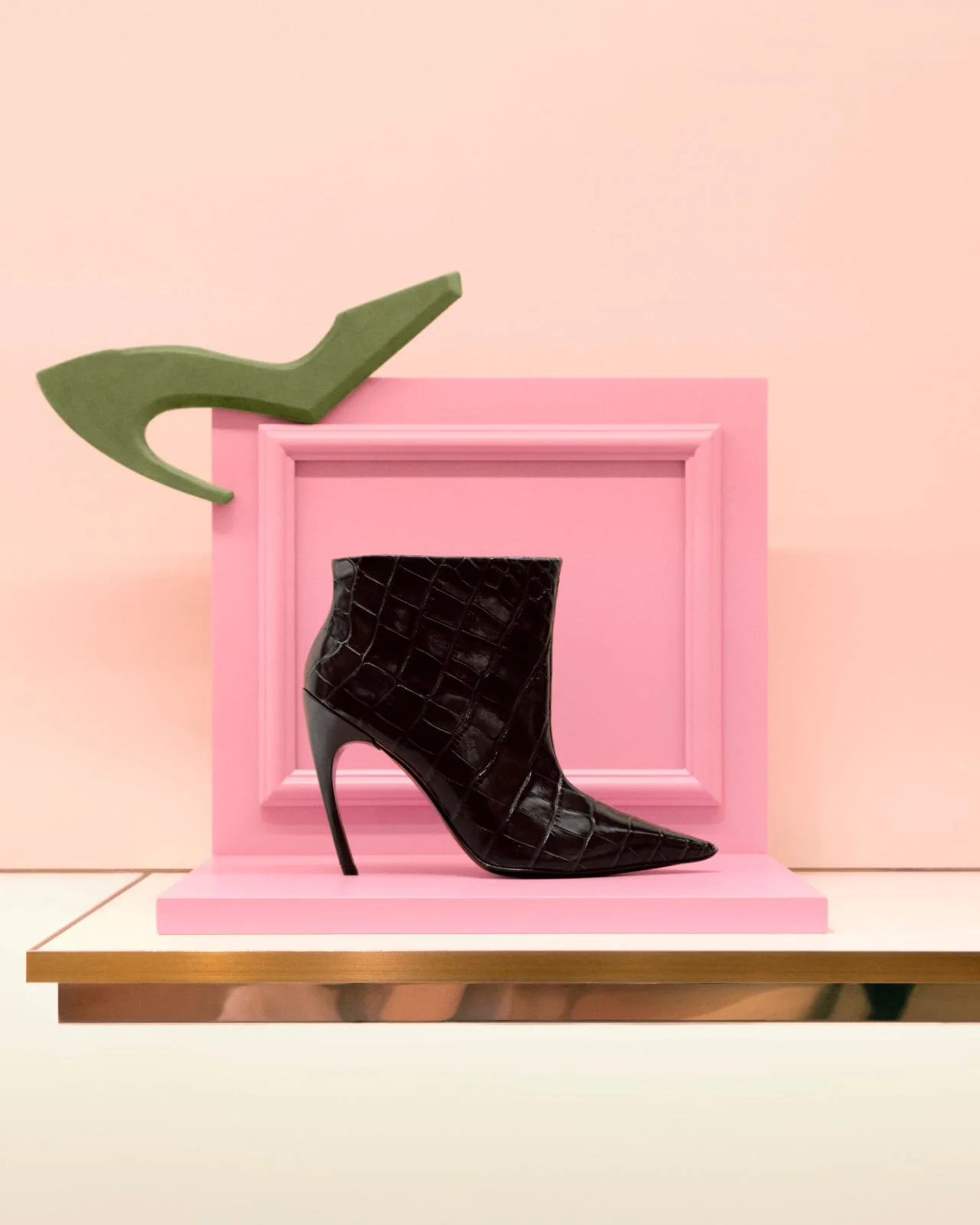 Black Roger Vivier Choc heel ankle boot displayed against pink and green sculptural set