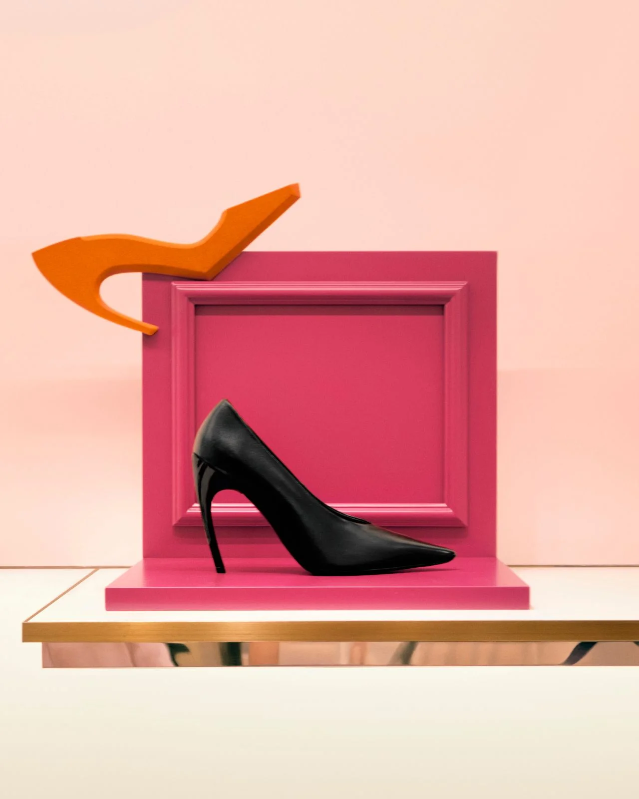 Black Roger Vivier Choc heel pump displayed against pink and orange sculptural set