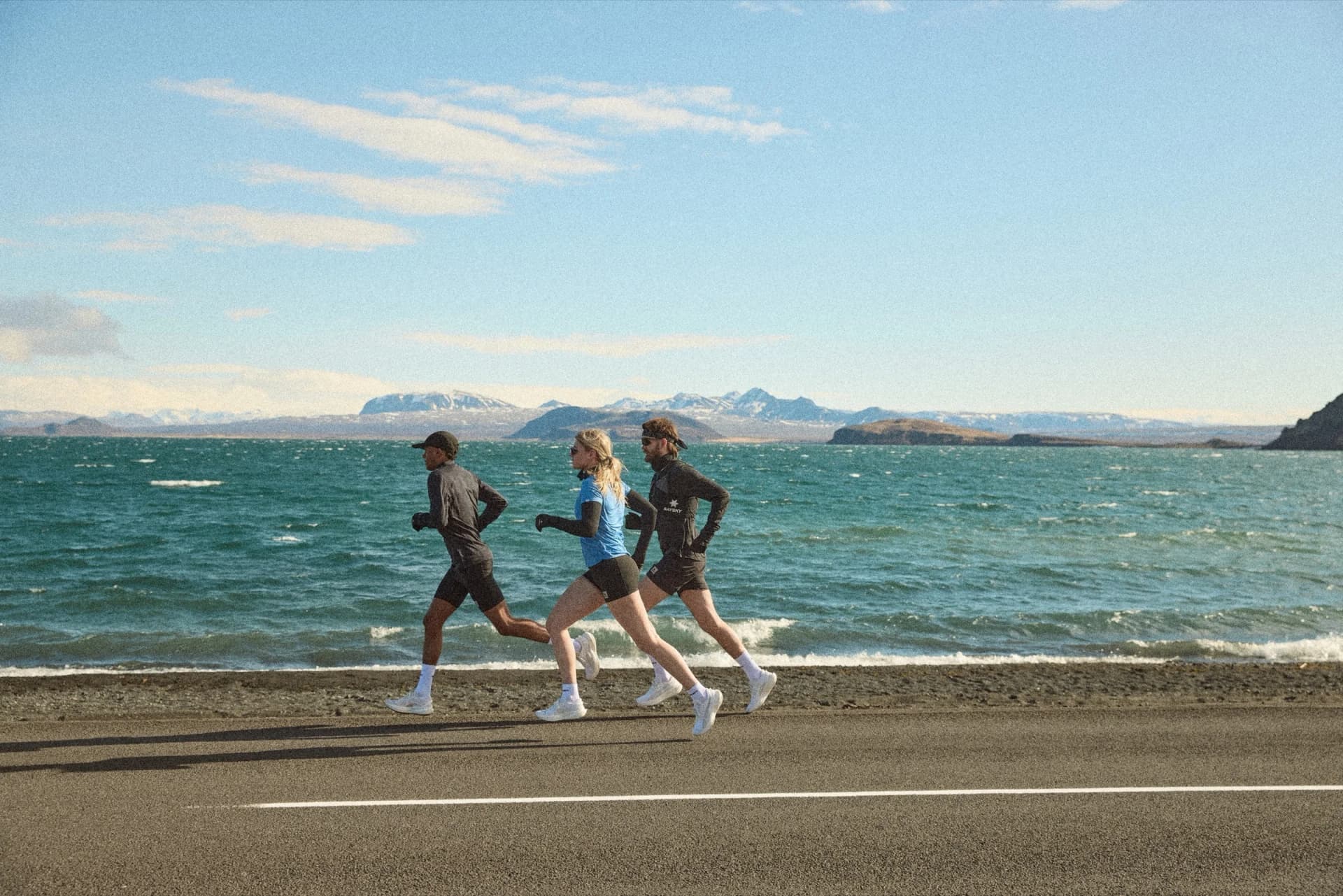 Three runners in SAYSKY Flow apparel on a coastal road near Reykjavik