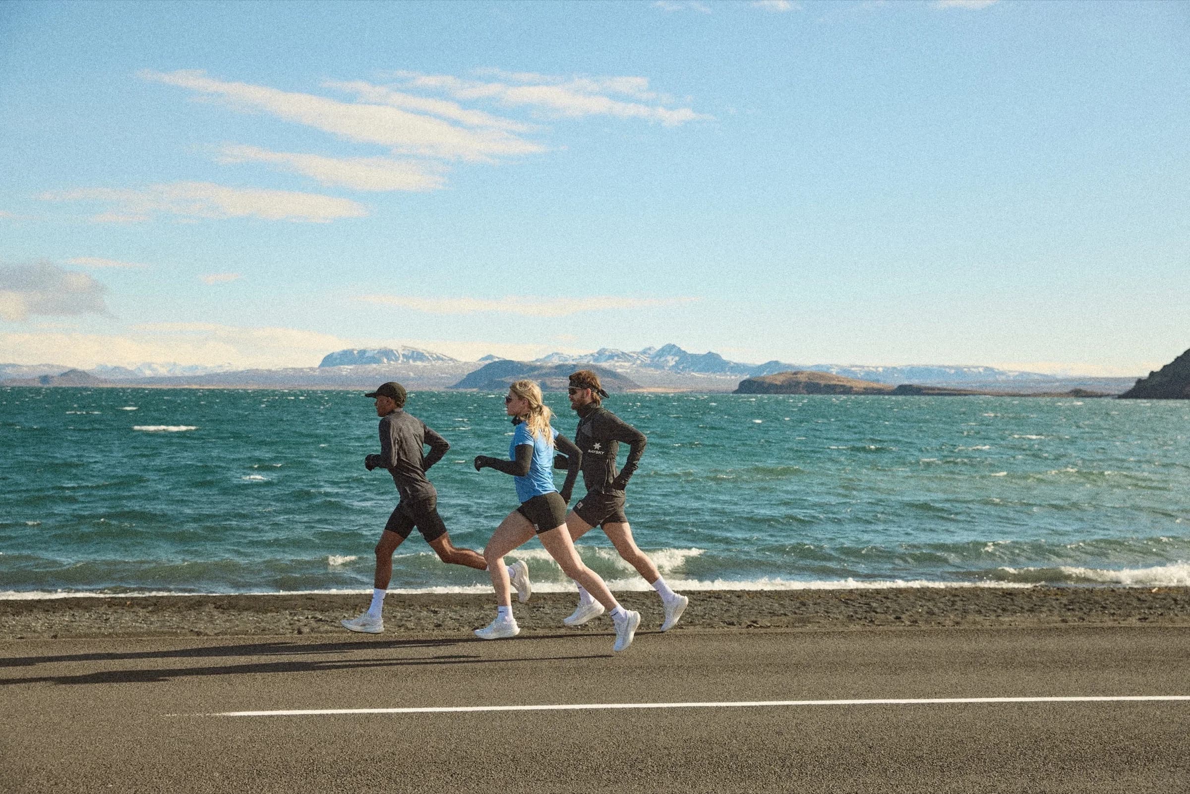 Three runners in SAYSKY Flow apparel on a coastal road near Reykjavik