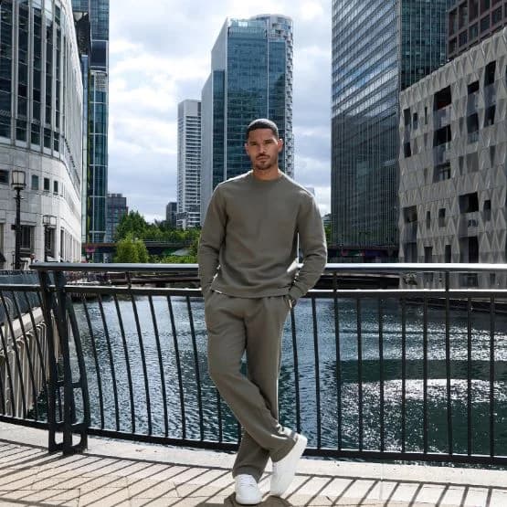 Model in a grey Gym King tracksuit beside an urban waterfront
