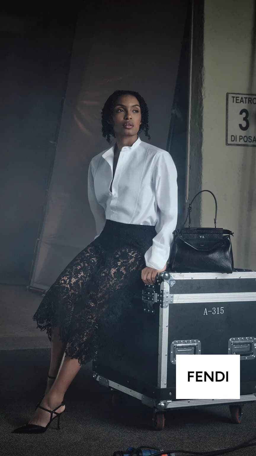 Fendi My Peekaboo campaign with a woman seated on a studio equipment case beside a personalized black bag