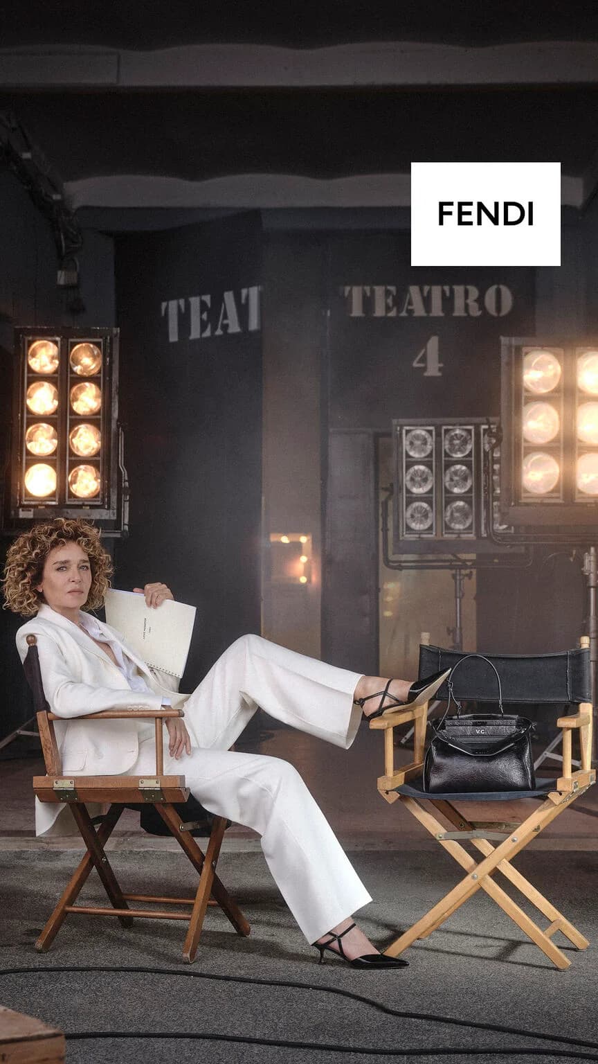Fendi My Peekaboo campaign with a woman in a white suit seated beside a personalized black bag on a studio chair