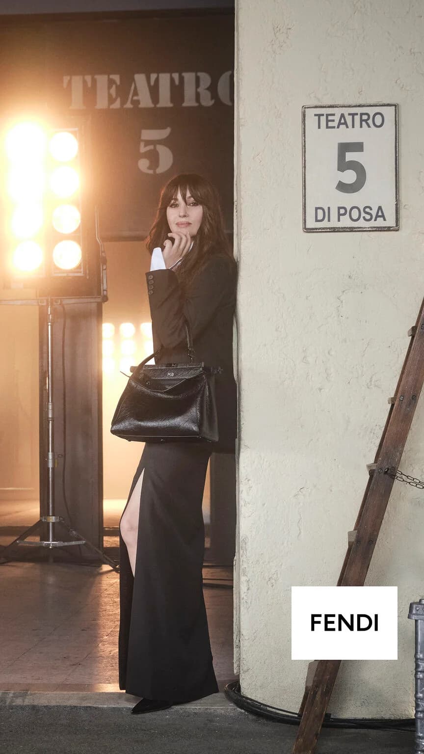Fendi My Peekaboo campaign with a woman in a black suit carrying a personalized bag beside a studio doorway