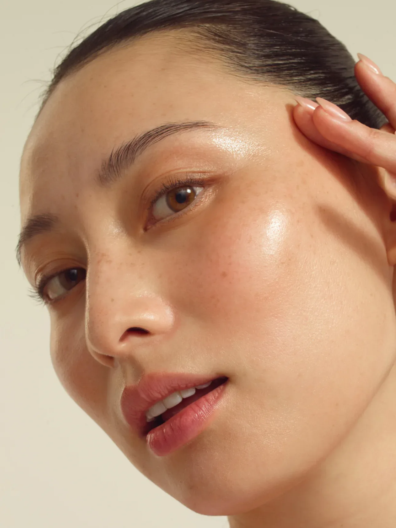Close-up portrait of a freckled model touching her temple in the ASICS campaign