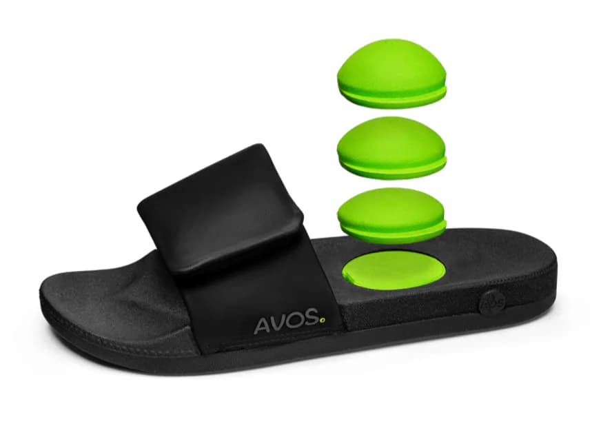 Black AVOS slide with three removable green acupressure pods above the heel opening