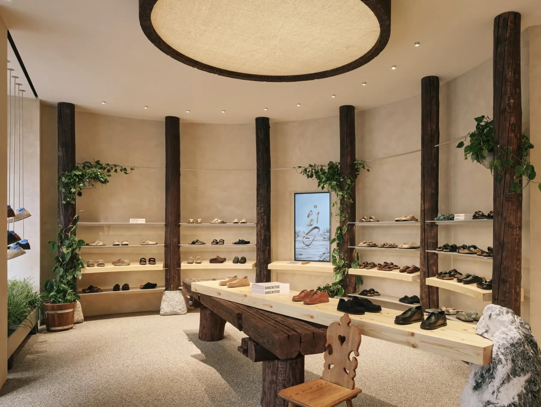 Birkenstock Zurich store with timber posts, plant-lined shelves, and a long wood table