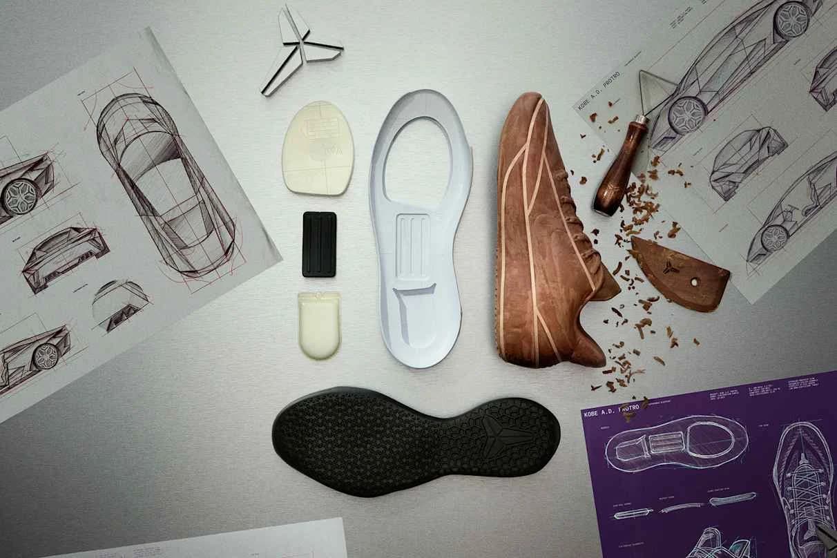 Nike Kobe A.D. Protro design components, a wooden shoe model and technical drawings lie on a work surface.