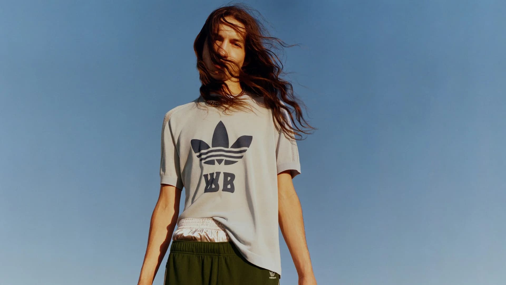 Model wearing a white adidas x Wales Bonner T-shirt against a blue sky