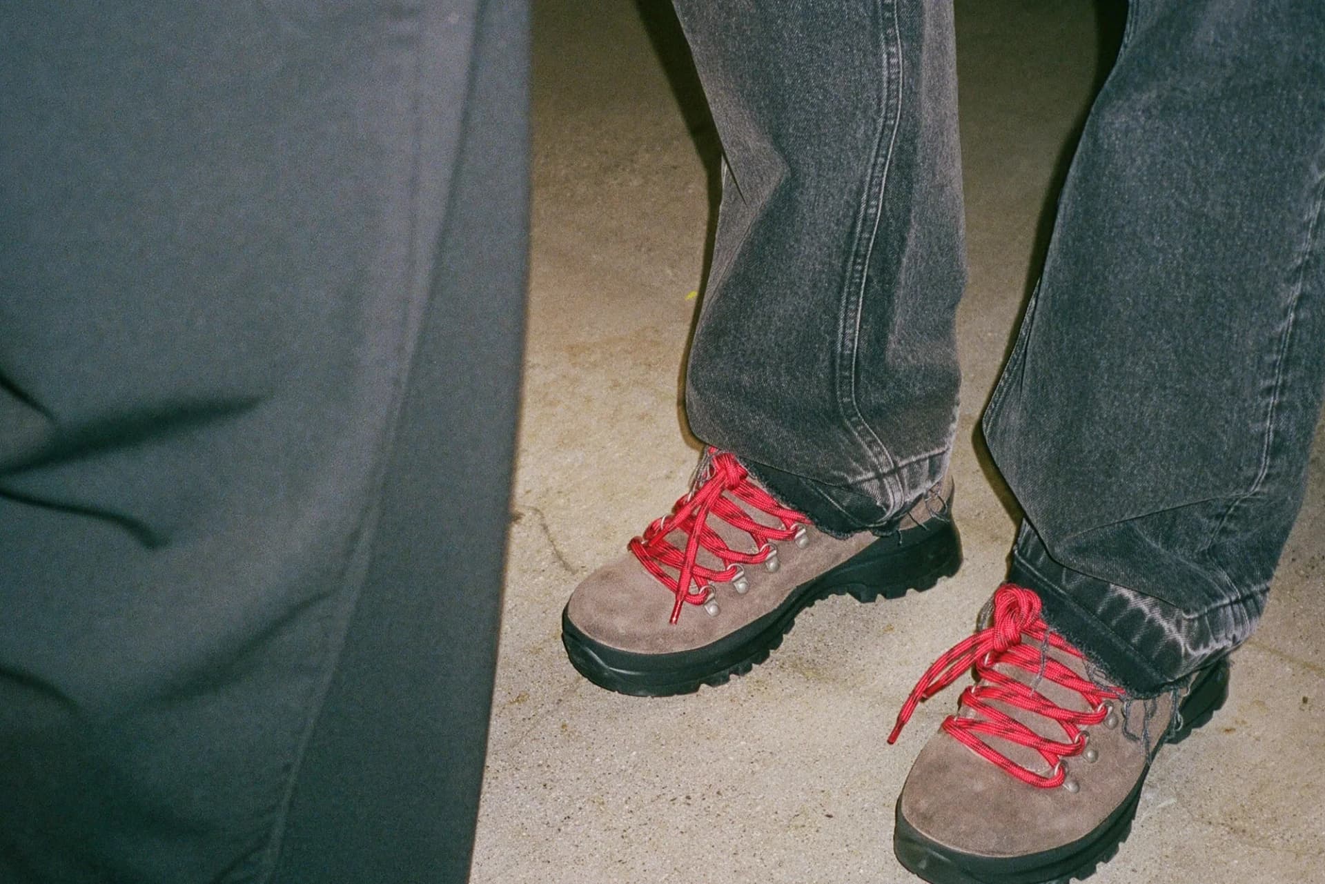 Represent suede lace-up Wrap Boot with red laces, worn with loose dark denim