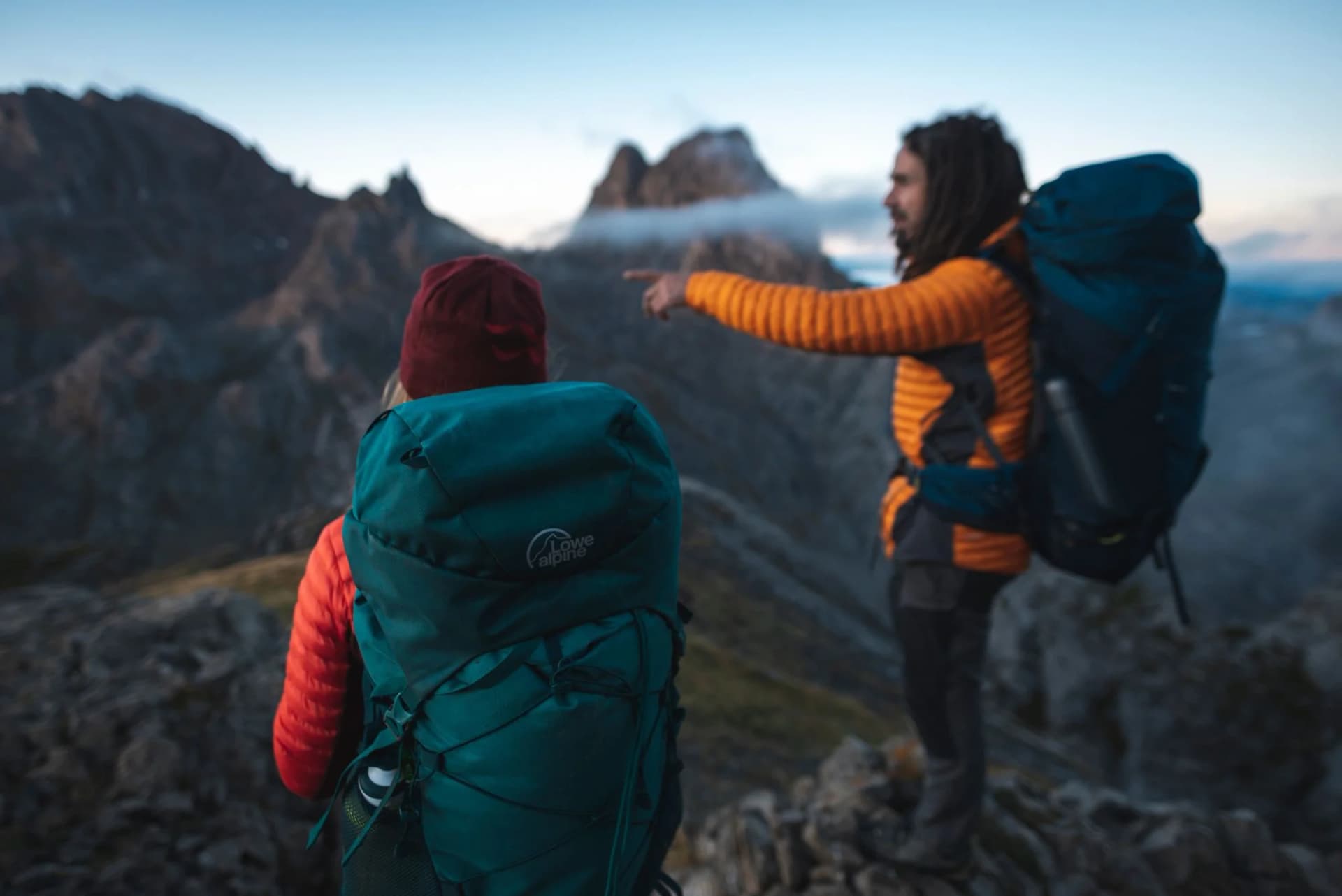 Two hikers carrying Lowe Alpine trekking packs in a mountain landscape