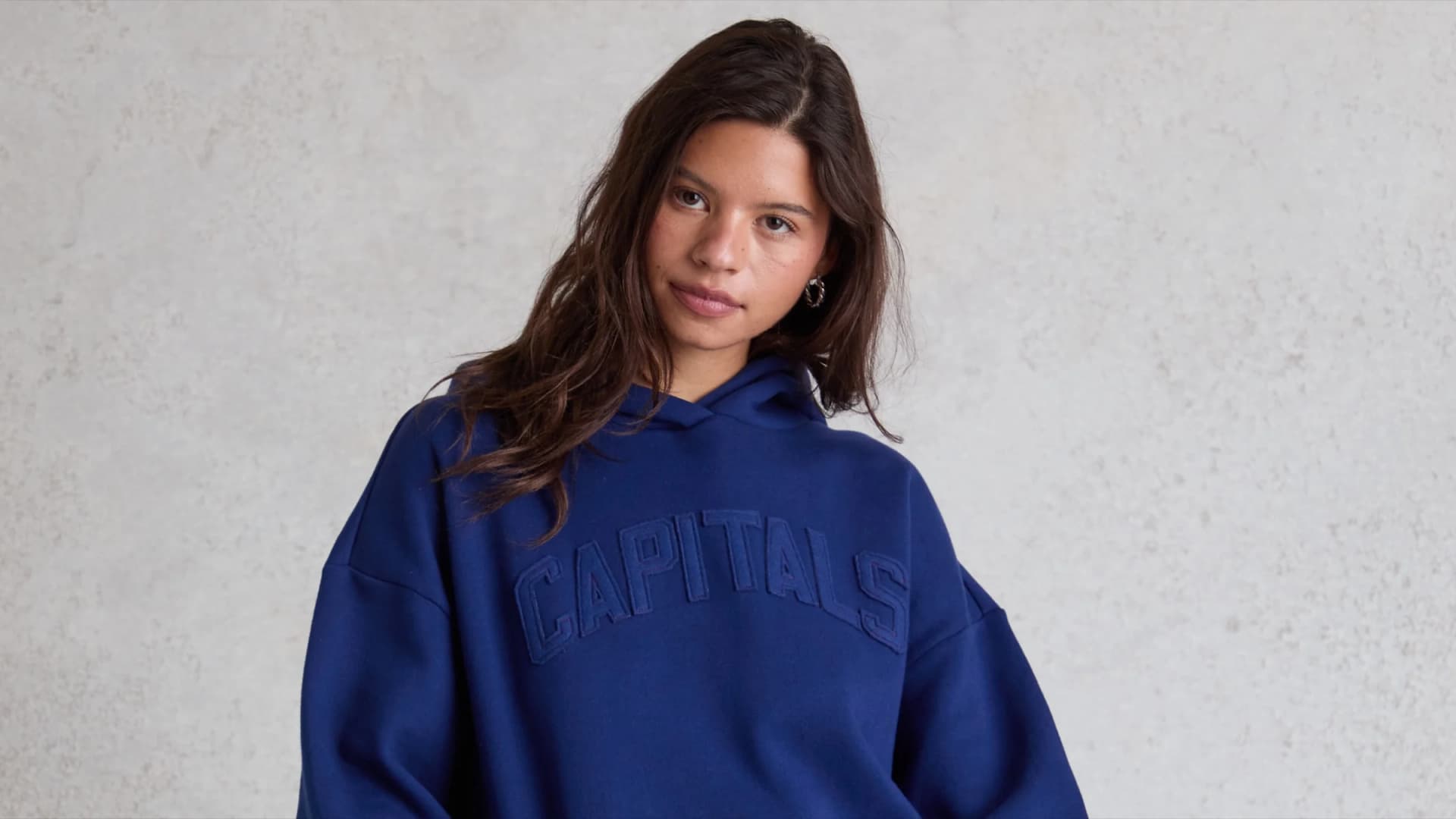 Landscape crop of a model wearing a blue Washington Capitals hoodie in Pacsun and The Wild Collective’s NHL campaign