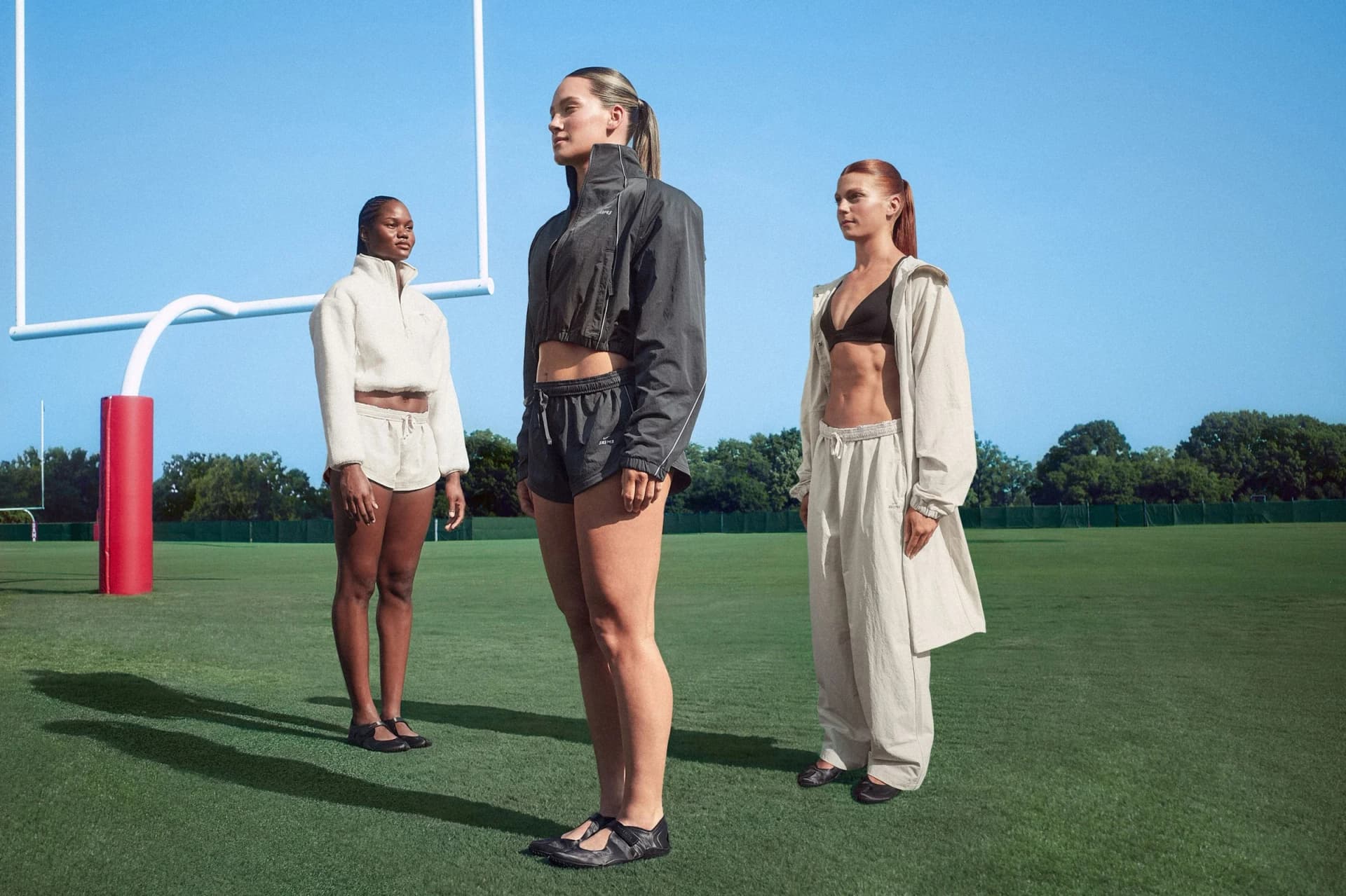 NikeSKIMS campaign cast wears seasonal outerwear on a football field.