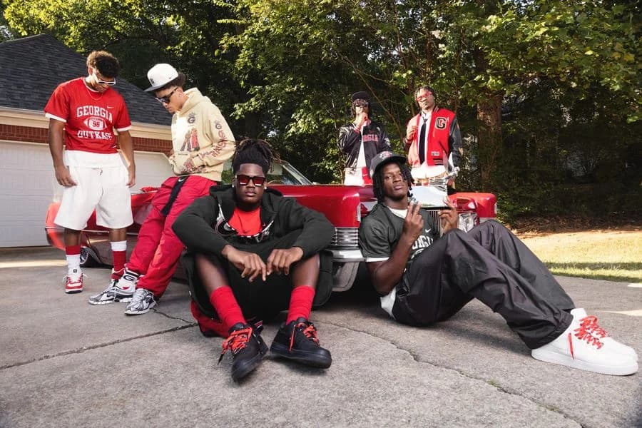 Six Georgia football athletes wear the Nike Georgia and Outkast apparel collection beside a red car
