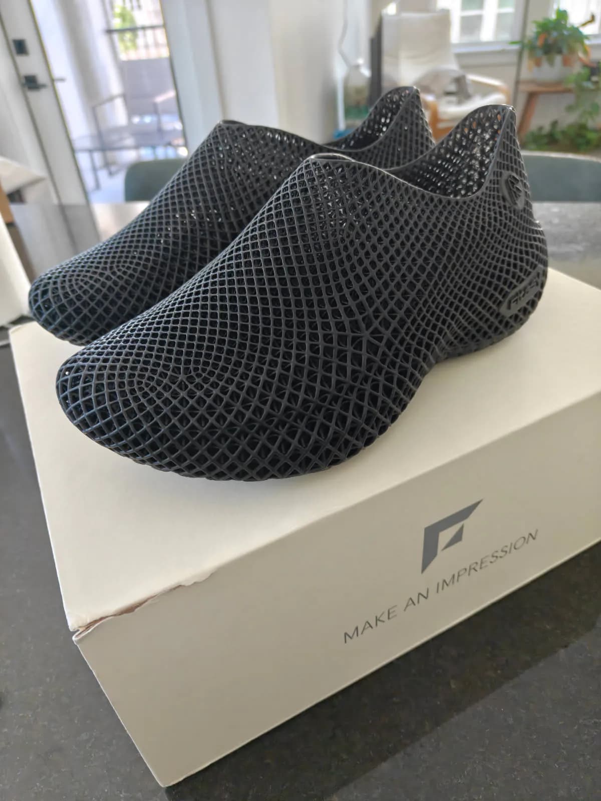 Pair of black Fitasy Stride 1.0 lattice recovery shoes resting on their box