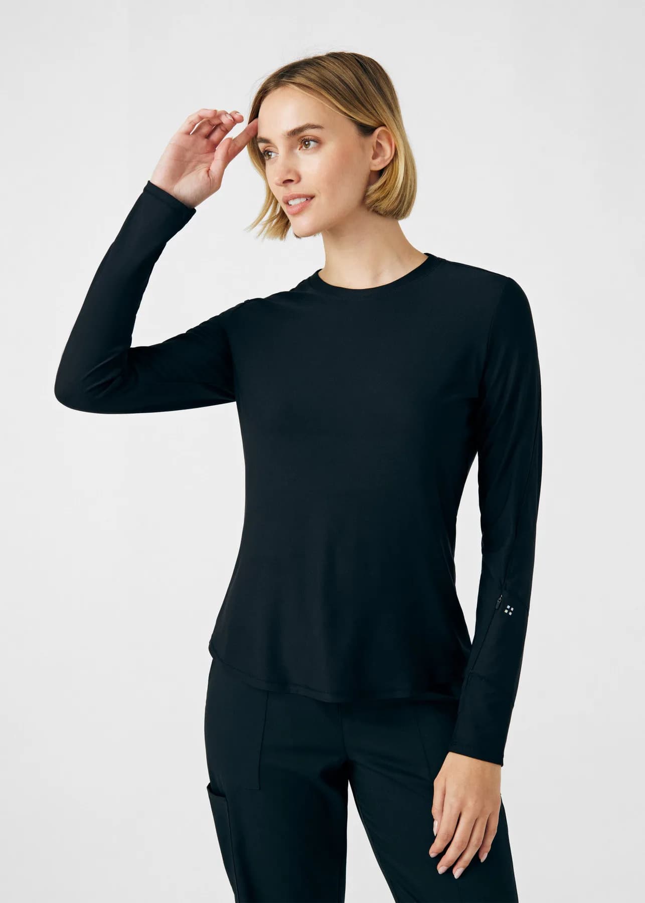 Woman modeling a fitted black Kindthread long-sleeve scrub top