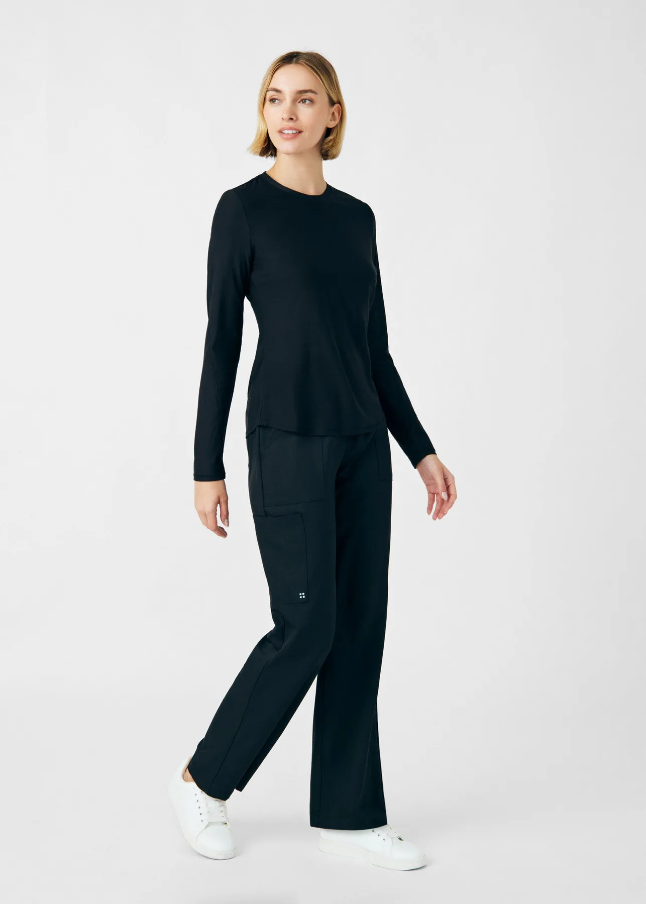 Woman walking in black Kindthread scrubs and white sneakers