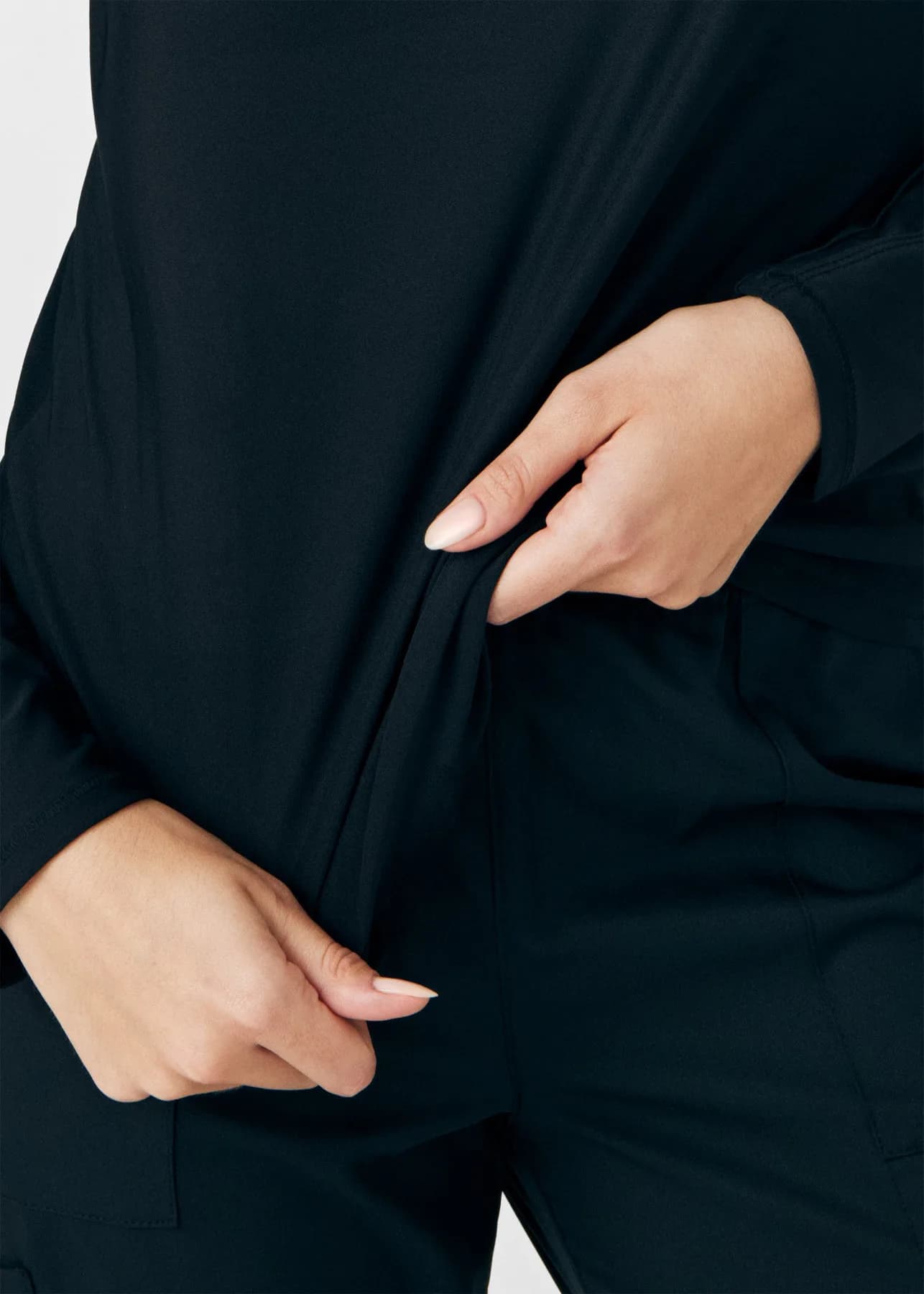 Close-up of hands demonstrating the stretch of a black Kindthread scrub top