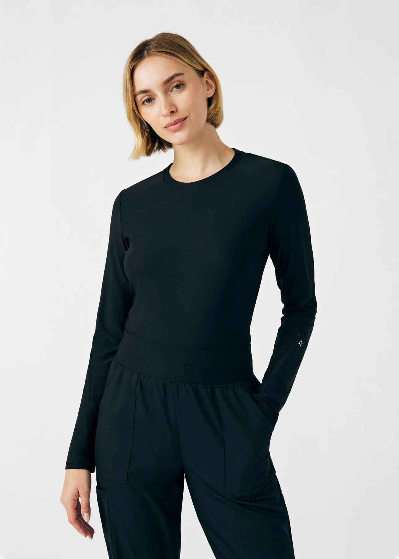 Woman wearing a black Kindthread long-sleeve scrub top and pants