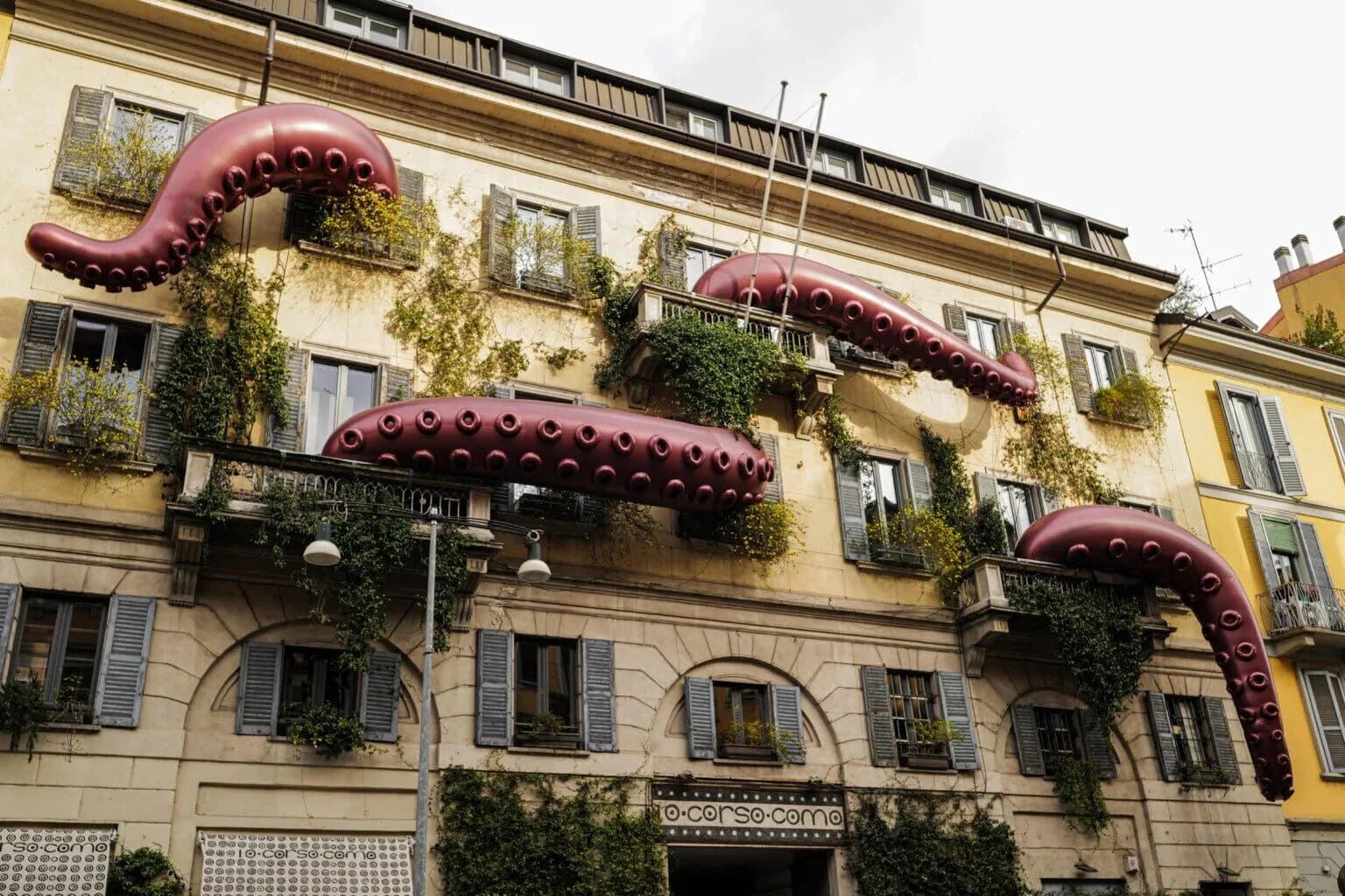 Giant purple inflatable tentacles stretching across a Milan building facade