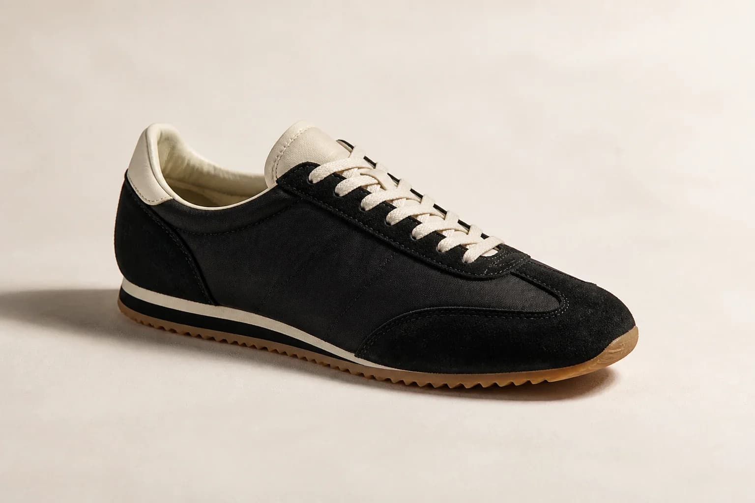 Unbranded slim black nylon and suede 1970s-style track sneaker on a warm white set