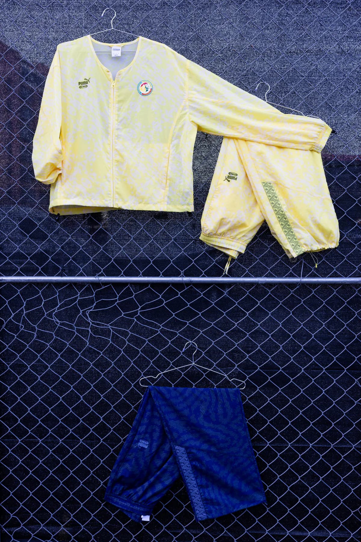 Yellow PUMA tracksuit and blue shorts from the Salehe Bembury collection on a fence