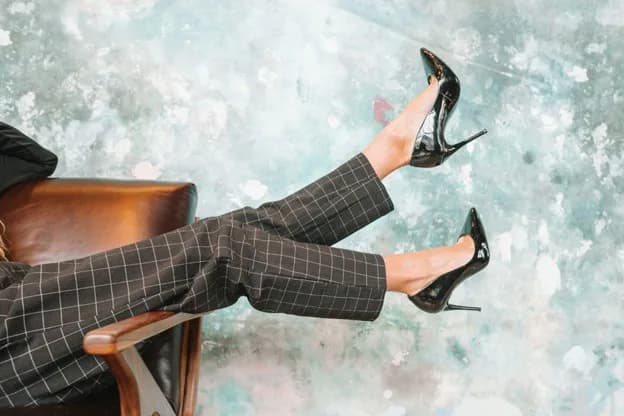 Woman seated in a chair wearing black patent high heels